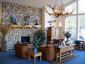 A stone fireplace, leather sofas, a wooden coffee table, and a large window. - Edgewater Inn Shady Cove (Shady Cove)