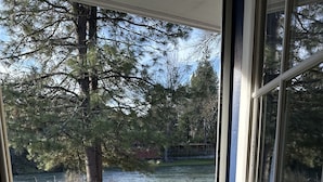 A view from inside a house looking out to a grassy area with a tree and a body of water. - Edgewater Inn Shady Cove (Shady Cove)