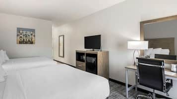 A hotel room with two beds, a desk with a chair, a television, and a mirror.