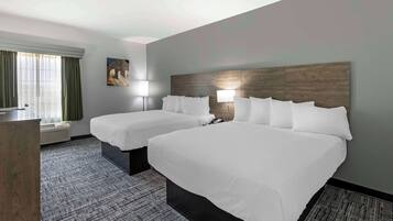 Habitación de hotel con dos camas, un escritorio y una ventana con cortinas.