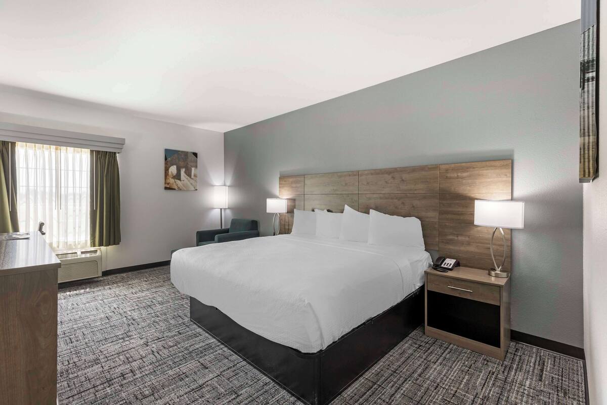 A hotel room with a large bed, bedside lamps, a desk, and a chair.