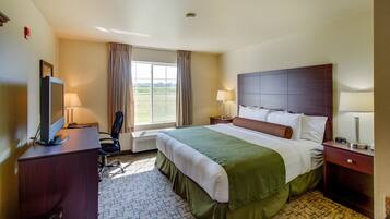 A hotel room with a bed, two bedside tables, a desk with a chair, a TV, and a window with curtains.