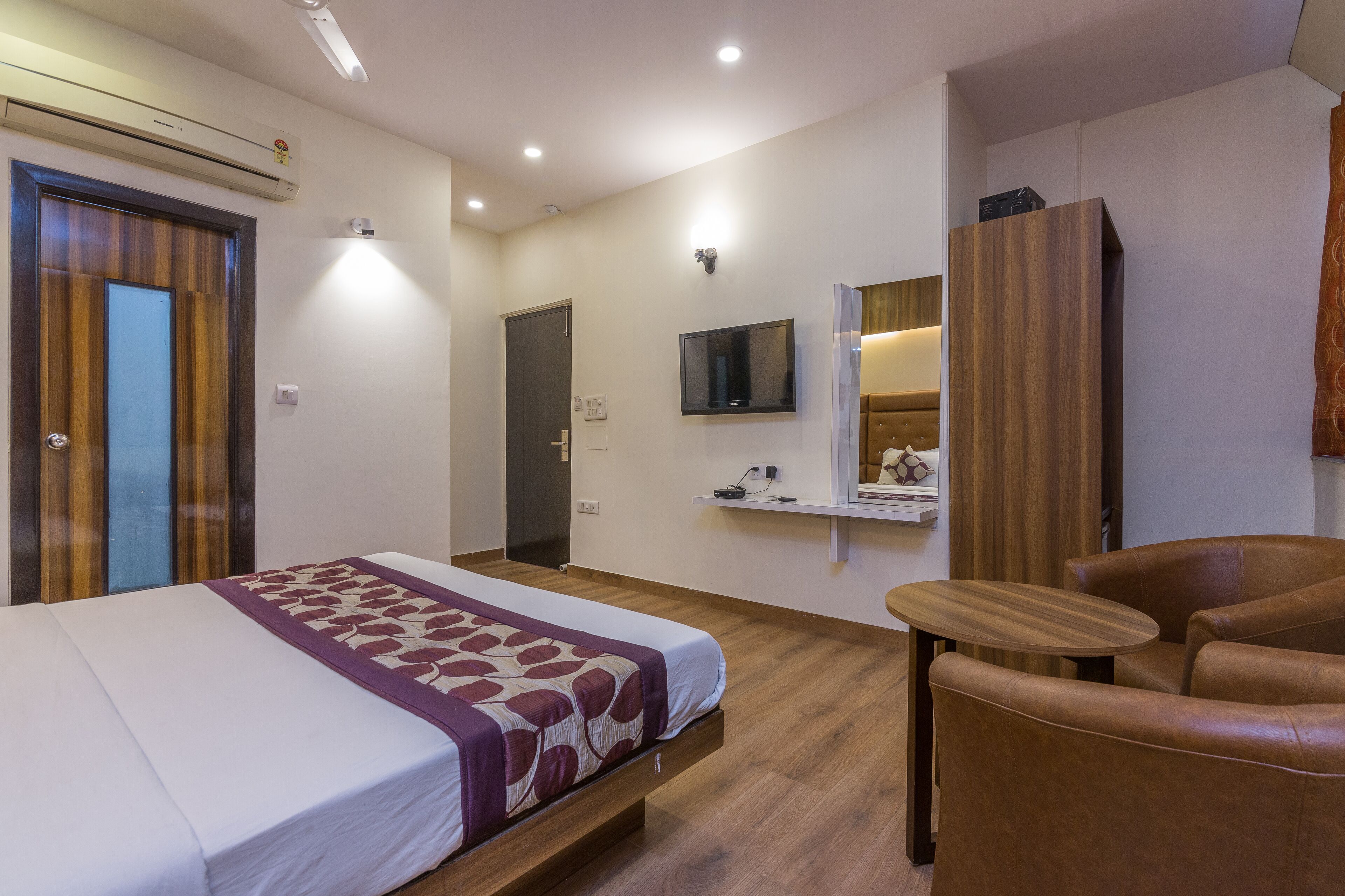 Una habitación de hotel con una cama, un sofá, un televisor y un espejo.