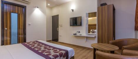 Una habitación de hotel con una cama, un sofá, un televisor y un espejo.