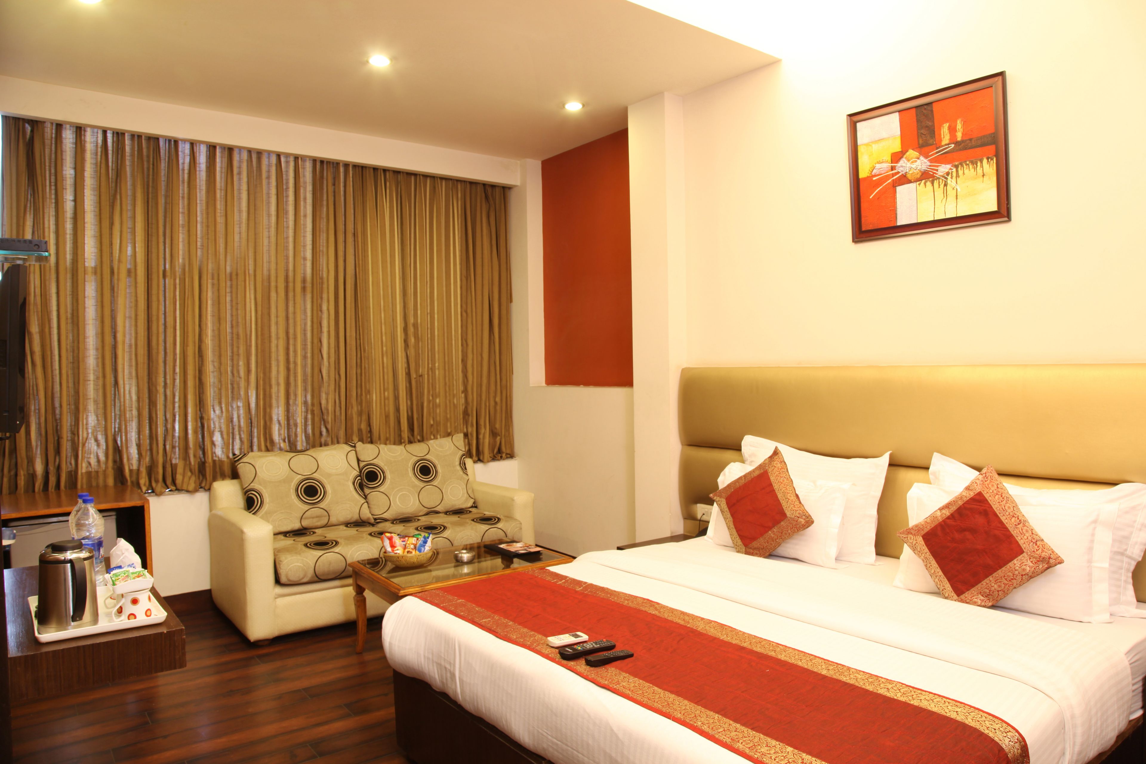 A hotel room with a large bed, a sofa, a coffee table, and a TV.