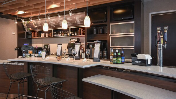 A bar area with a long counter, bar stools, and a menu board. - Courtyard Marriott Concord (Concord)