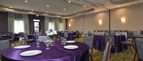 A conference room with round tables, purple tablecloths, and chairs.