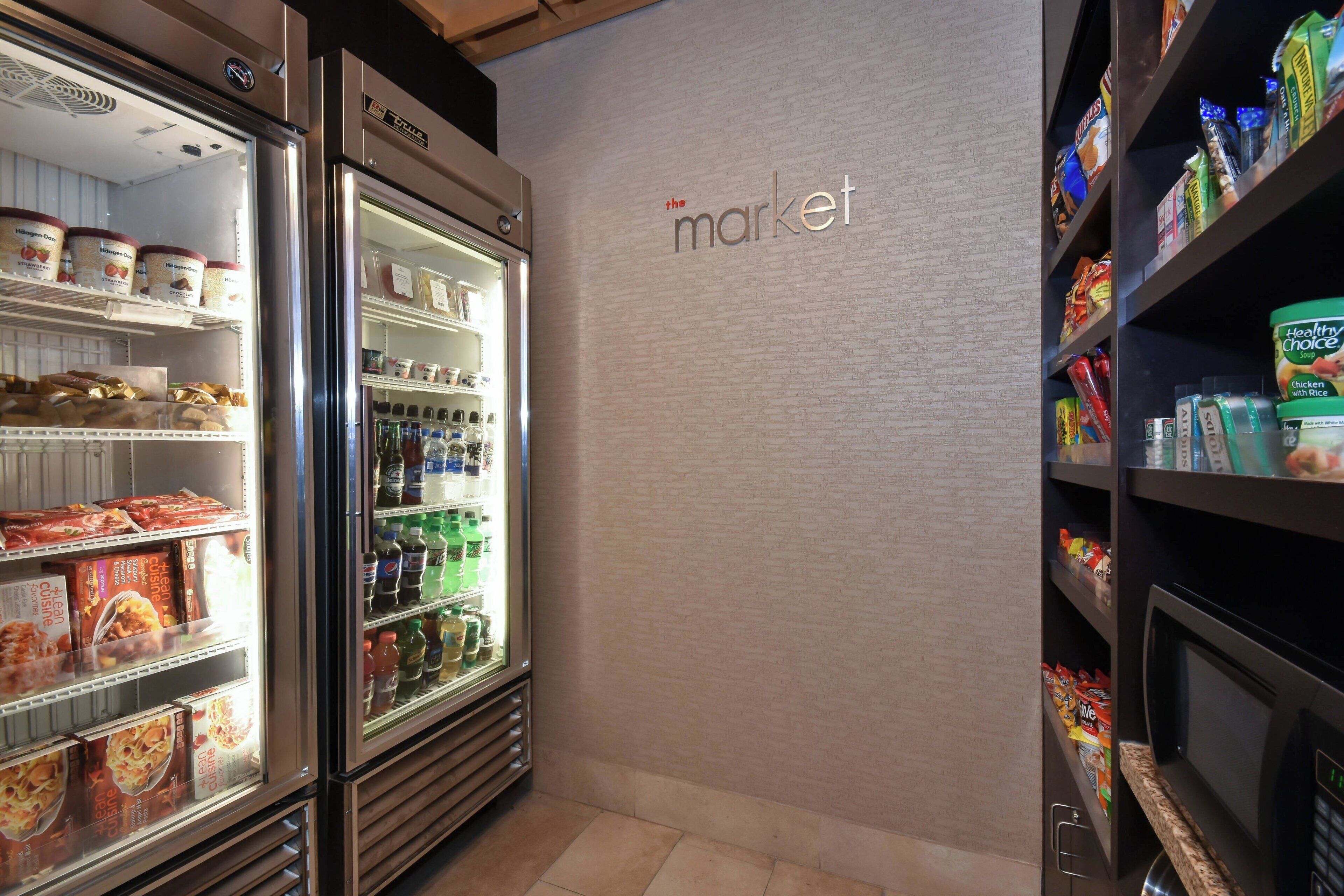 A refrigerated display case with various food items and a wall with the text 'the market'.
