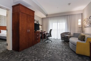 A hotel room with a bed, a desk, a chair, a sofa, and a wardrobe.