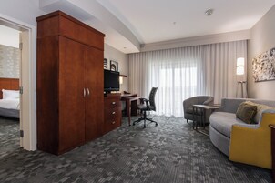 Una habitación de hotel con una cama, un escritorio, una silla, un sofá y un armario.