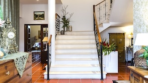 A spacious living area with a staircase, a wooden dresser, and a red carpet. - Quinta do Covanco (Alenquer)