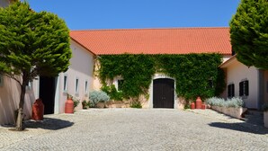 A courtyard with cobblestone paving, a building with a red-tiled roof, and greenery. - Quinta do Covanco (Alenquer)