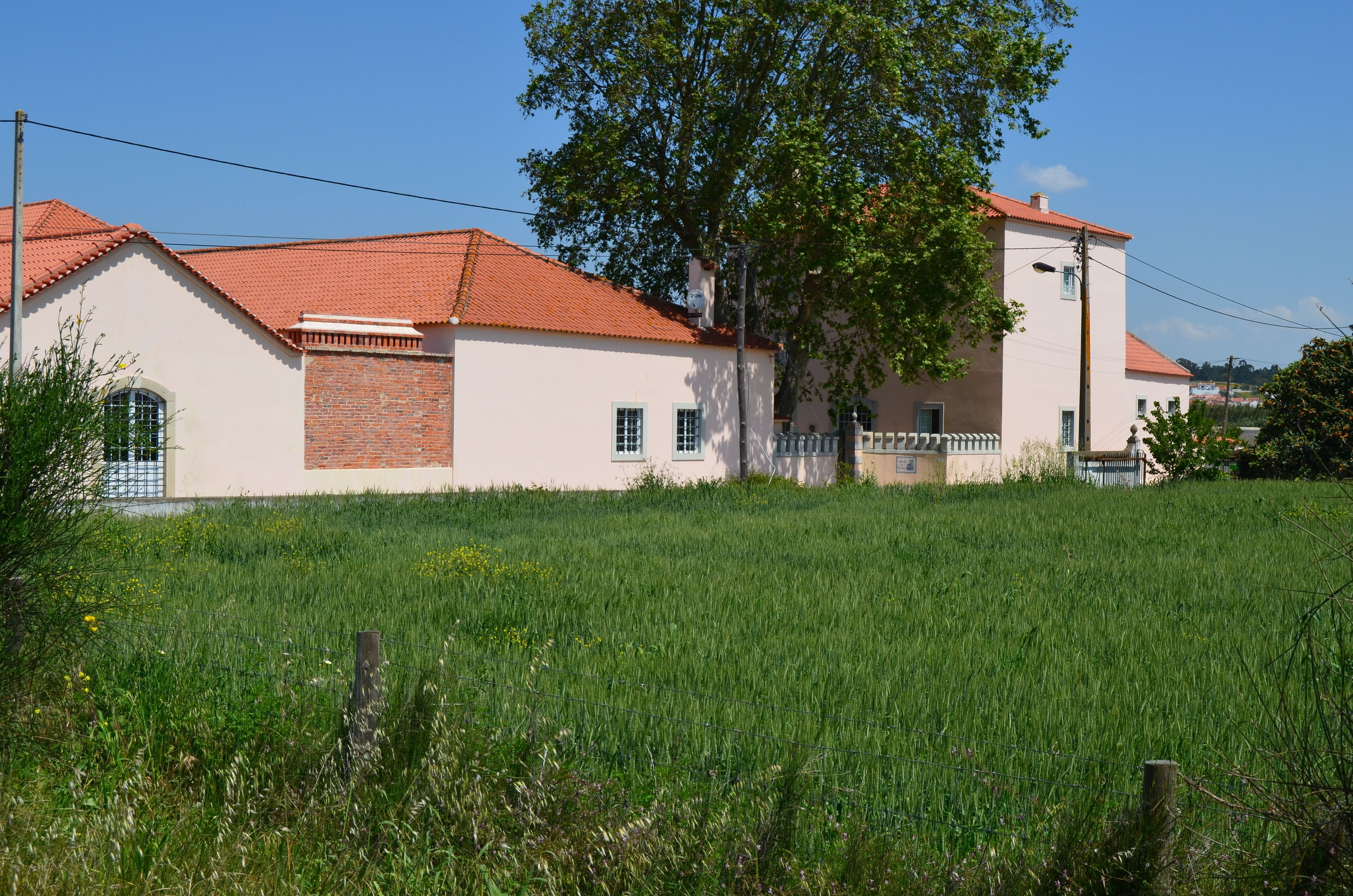 A two-story house with a red-tiled roof, a brick section, and a white facade.