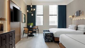 A hotel room with a bed, a desk, a chair, a TV, and a window.