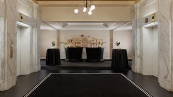 Eine geräumige Lobby mit Marmorwänden, einer Bar im Zentrum und einem Kronleuchter.