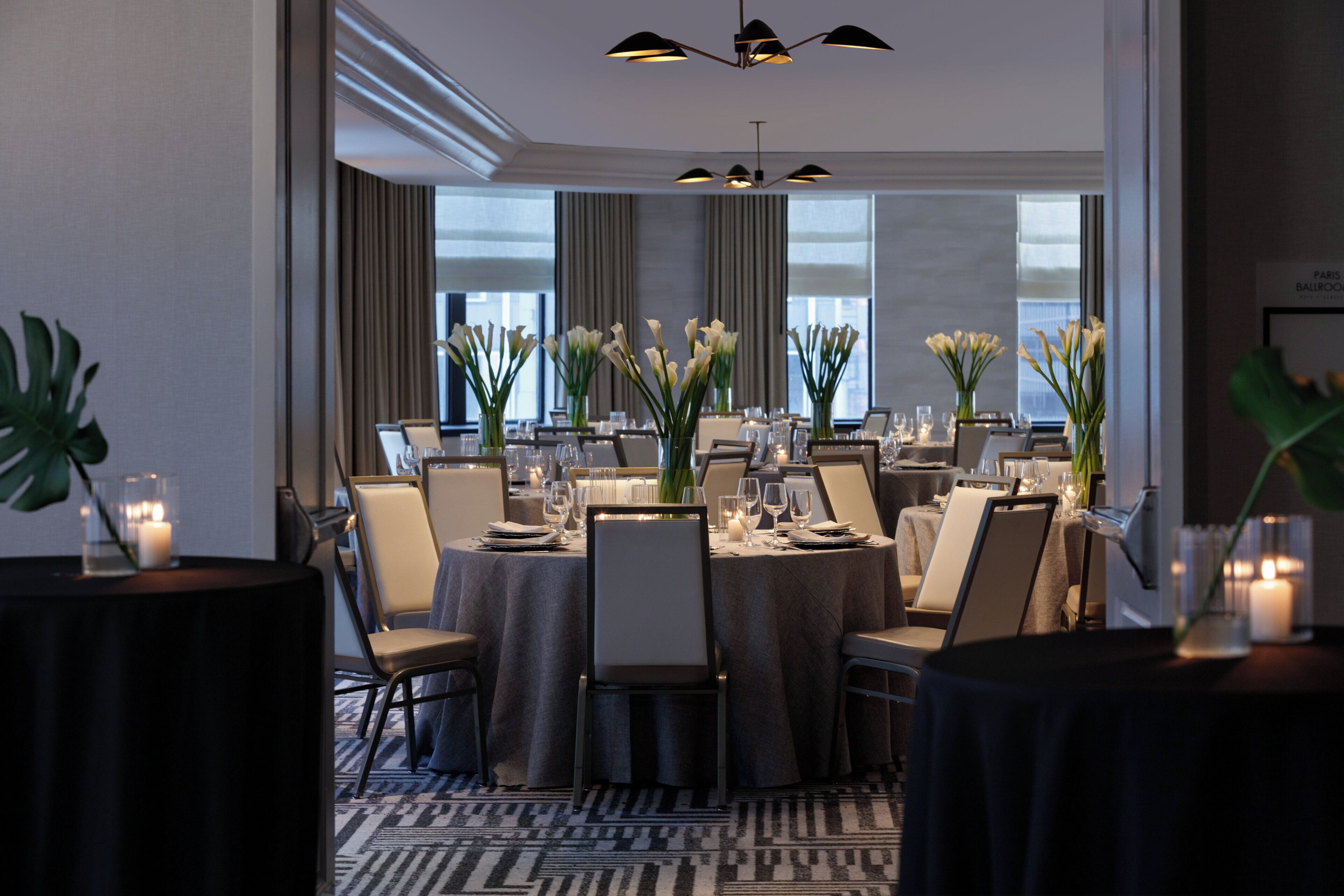 A dining area with round tables, chairs, and floral centerpieces.