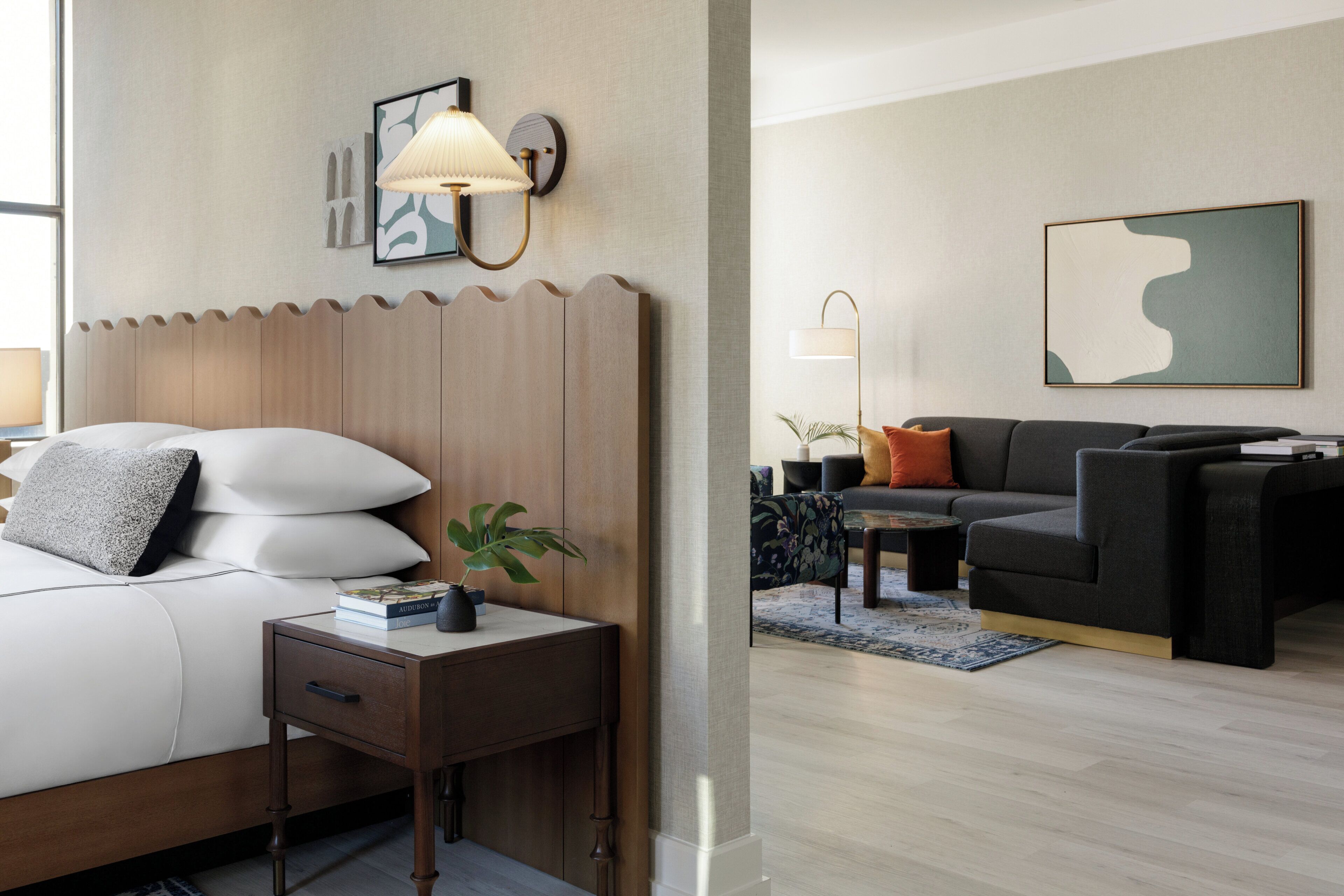 A hotel room with a bed, bedside table, lamp, and a wall-mounted artwork.