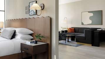 A hotel room with a bed, bedside table, lamp, and a wall-mounted artwork.