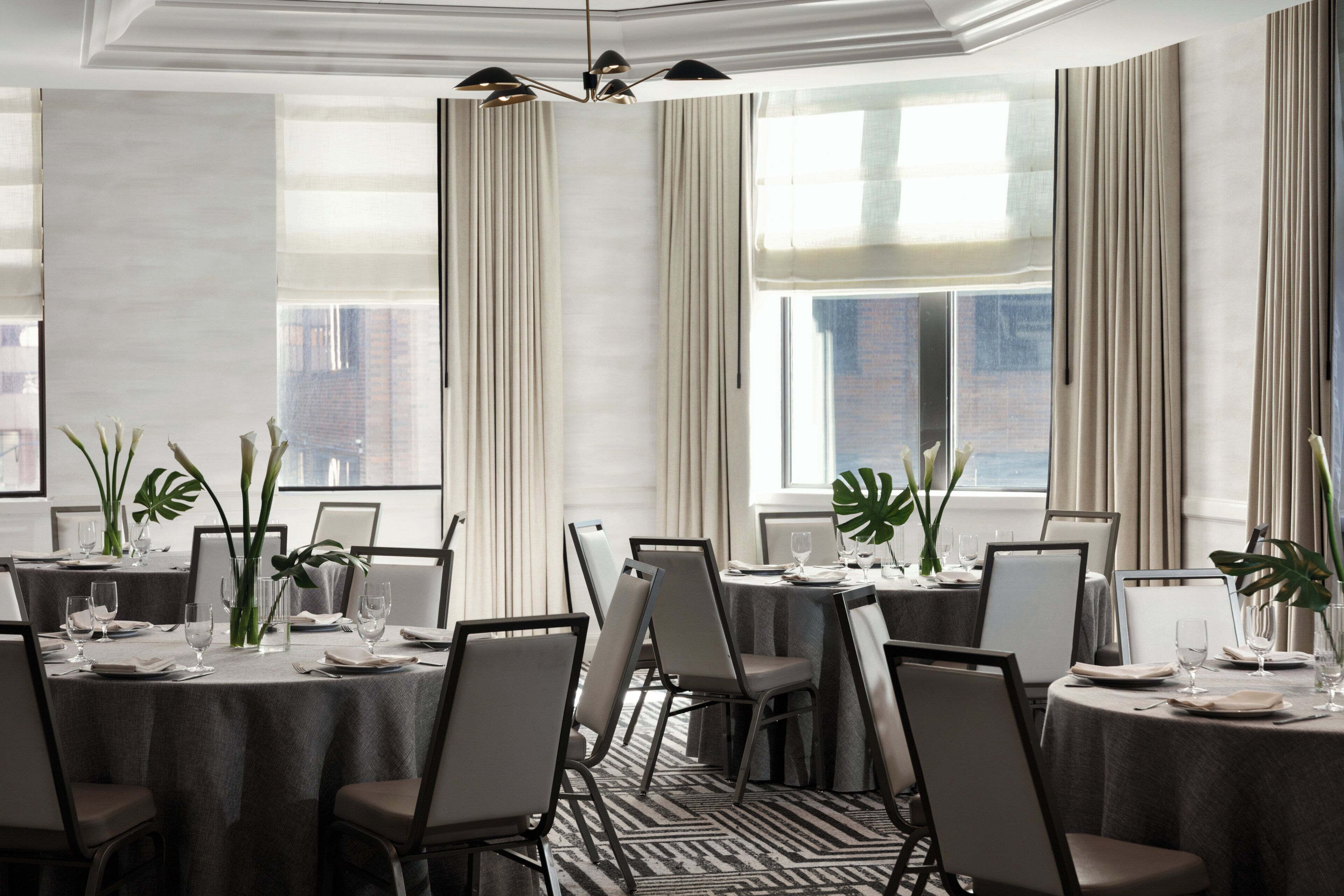 A dining area with round tables, chairs, and plants.