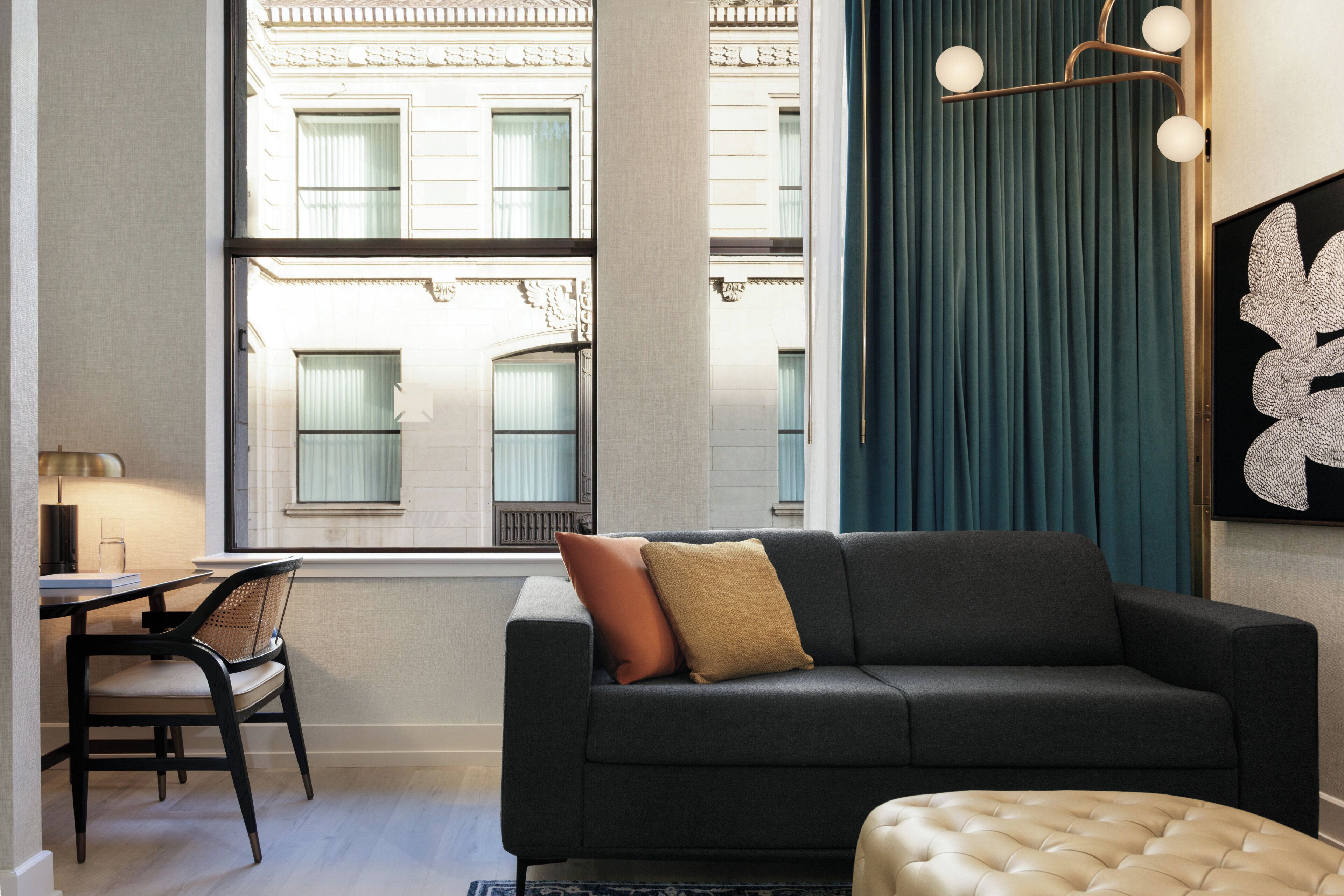 A modern living room with a sofa, a chair, a table, and a window with a view of buildings.