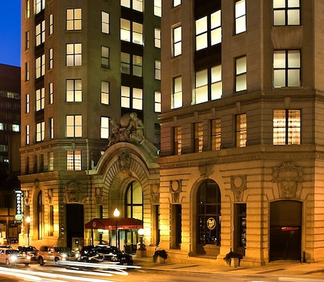 A multi-story hotel with illuminated windows, a prominent entrance with a canopy, and a statue above the entrance.