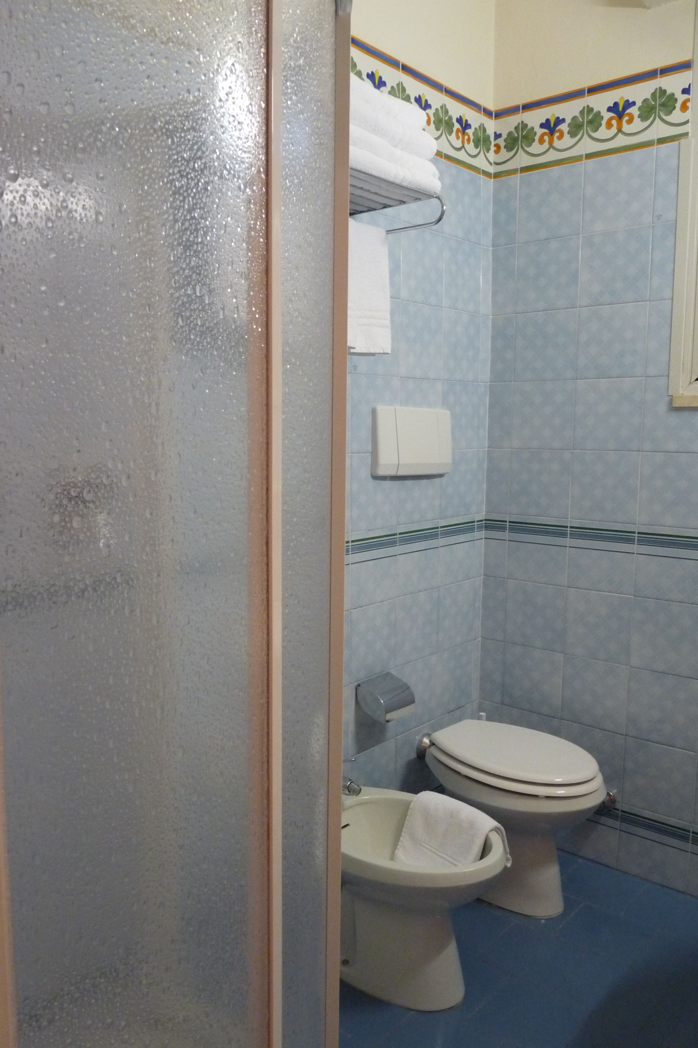 Un baño con inodoro, bidé y toallero.