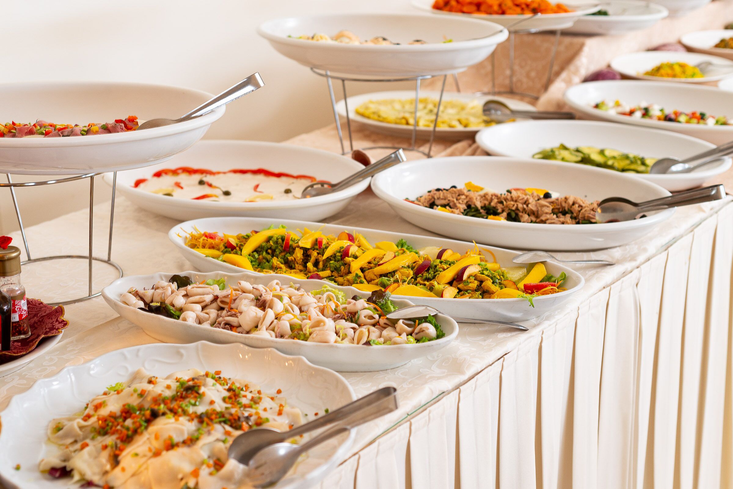 A buffet table with various dishes including salads, meats, and seafood.