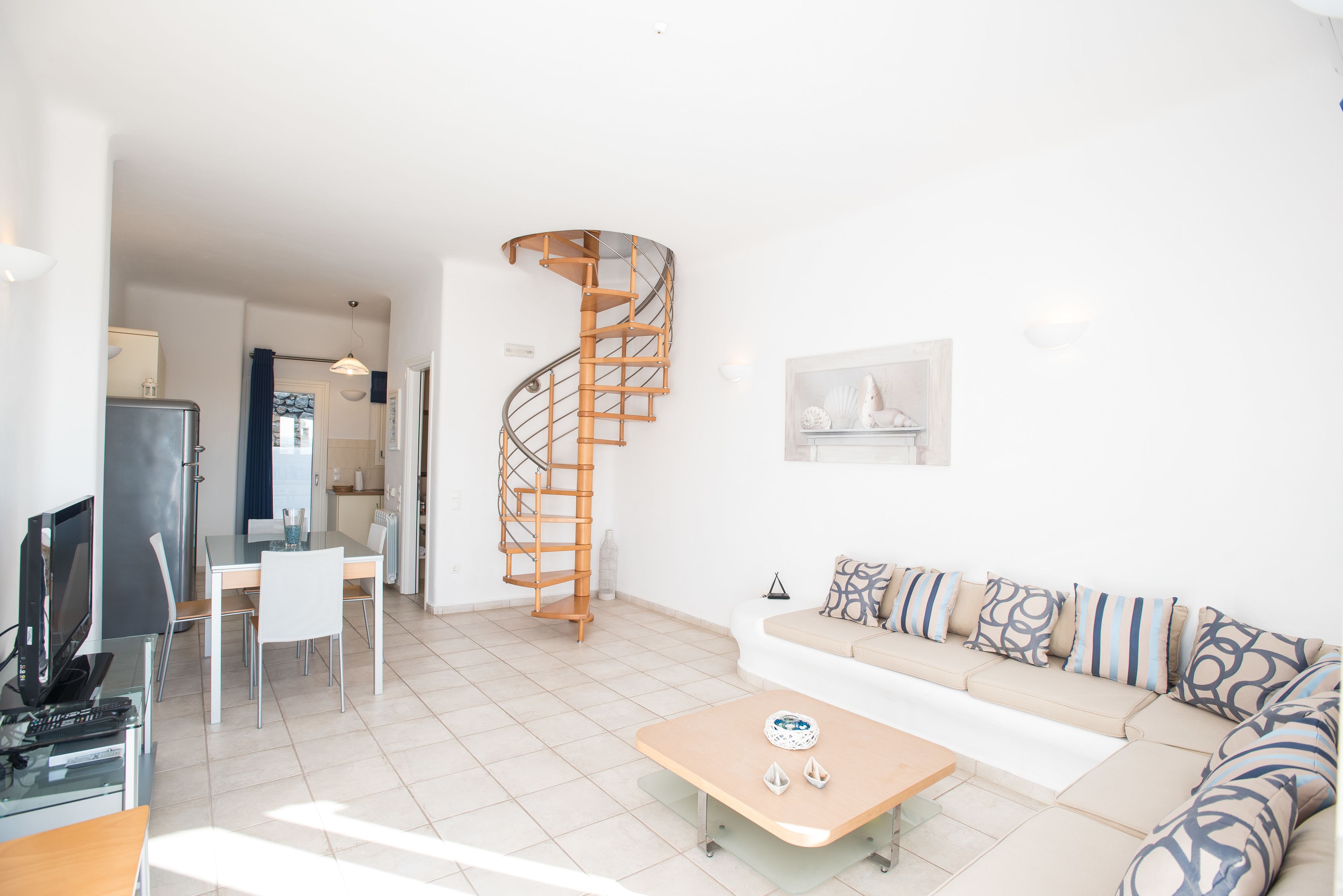 A modern living room with a spiral staircase, a sofa set, a dining area, and a kitchen.