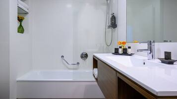 A modern bathroom with a white bathtub, a vanity with a mirror, and a shower area.