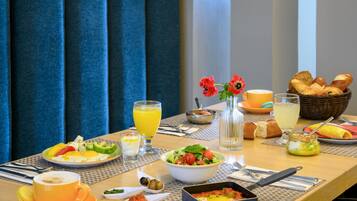 Una mesa de desayuno con diferentes platos, una taza de café y un vaso de zumo de naranja.