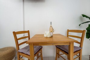 A wooden table with two chairs, a bottle of wine, and a bouquet of flowers. - Adulo Apartments (Rockley)