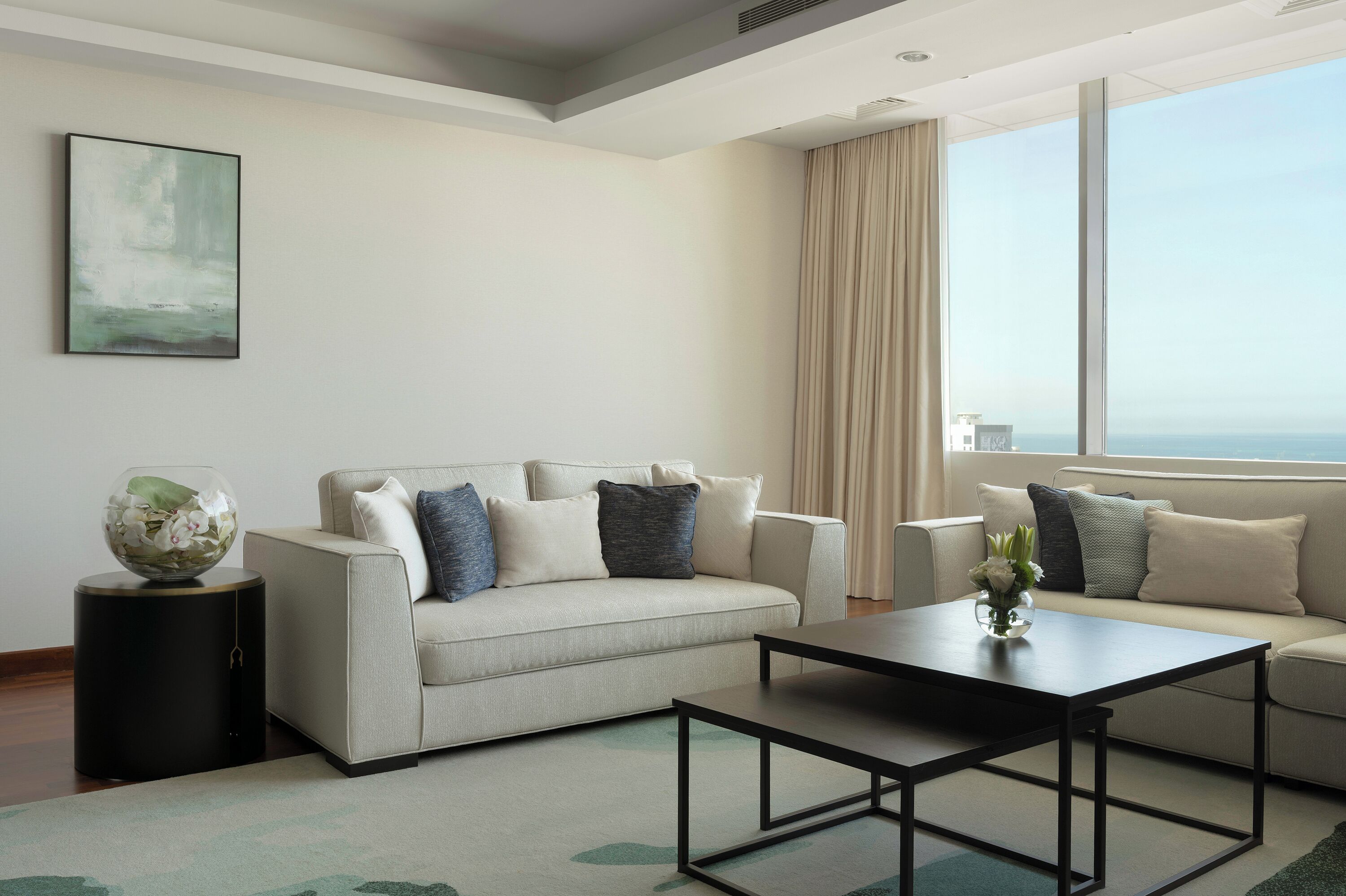 Una sala de estar moderna con un sofá, una mesa de centro y un amplio ventanal con vistas.