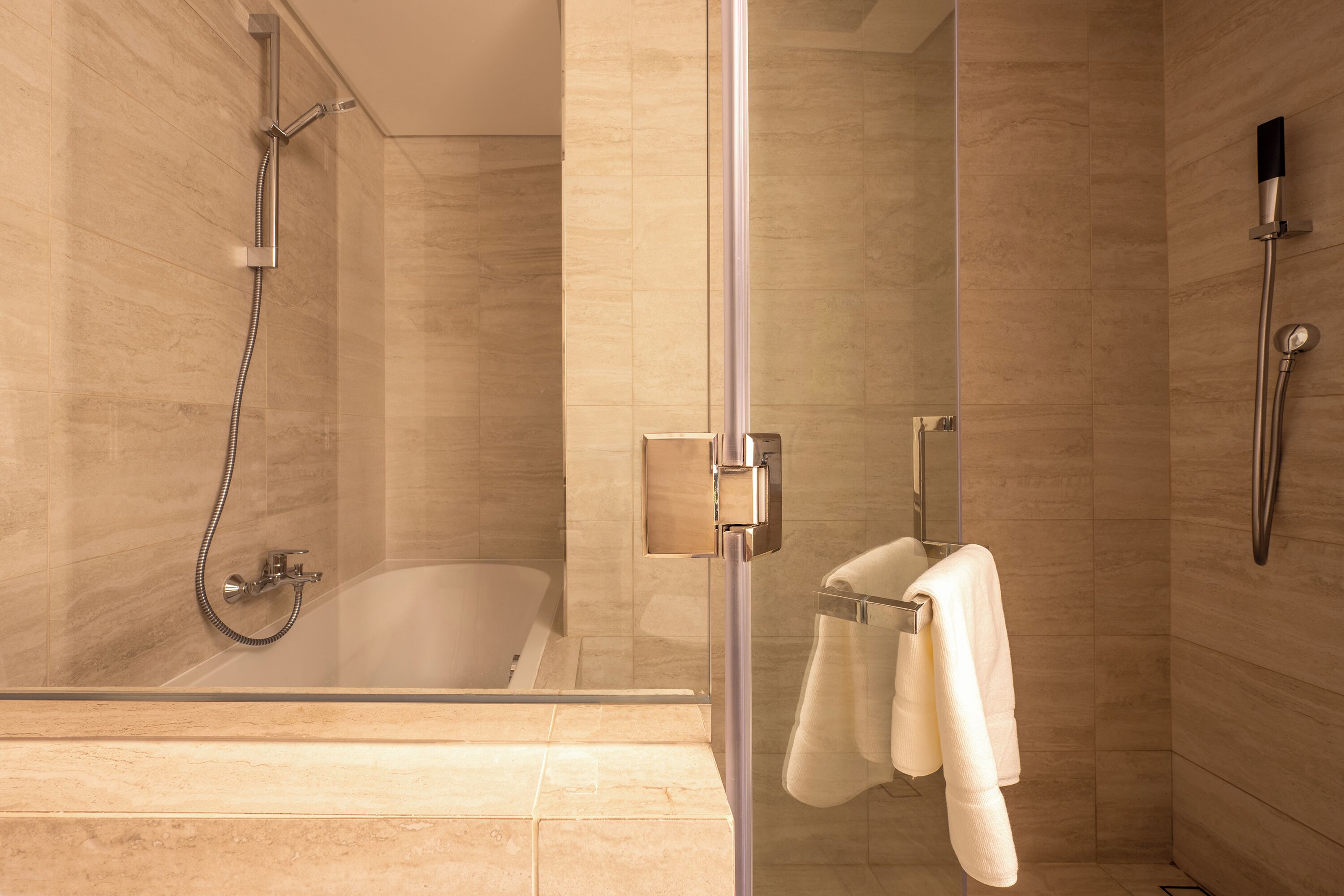 Un baño moderno con ducha acristalada, bañera y toallero.
