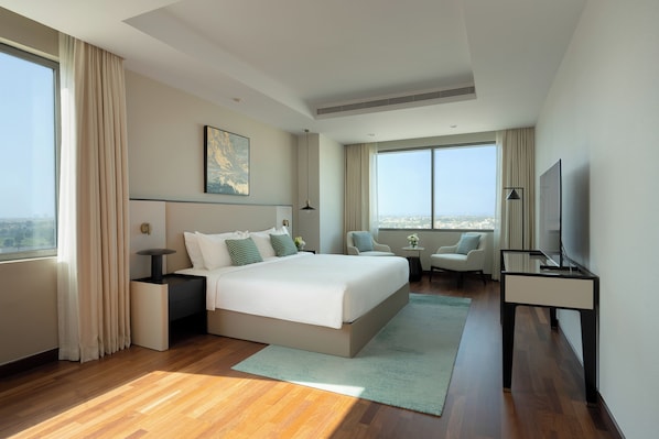 Una habitación de hotel moderna con una cama grande, un escritorio, una silla y un televisor.
