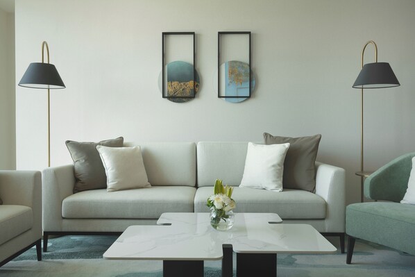 A modern living room with a sofa, two side tables, and a coffee table. - Fraser Suites Seef Bahrain (Manama)