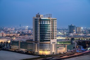 A high-rise hotel with a modern design, featuring a prominent sign at the top. - Fraser Suites Seef Bahrain (Manama)