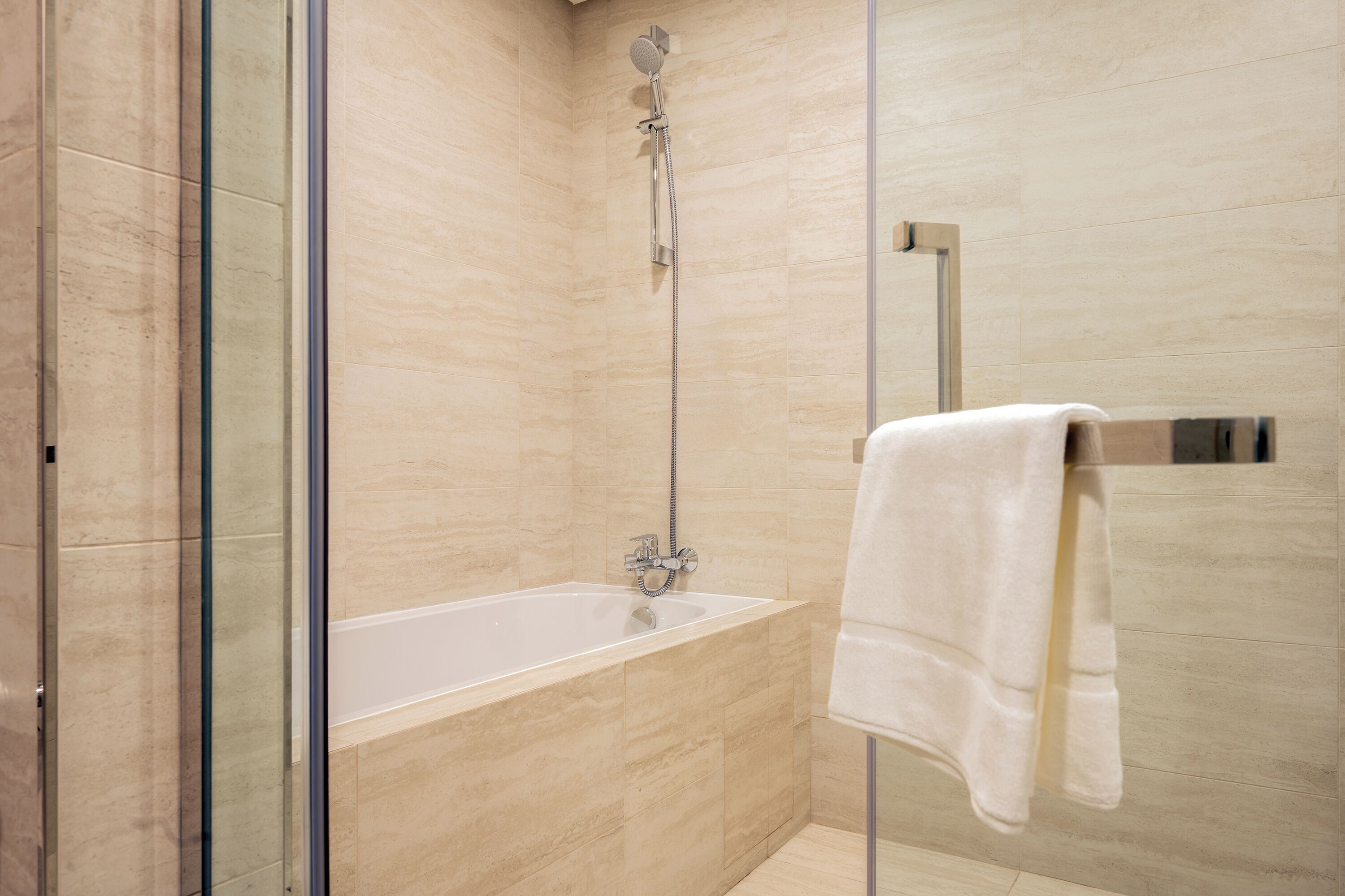 A modern bathroom with a glass-enclosed shower, a white bathtub, and a towel rack.