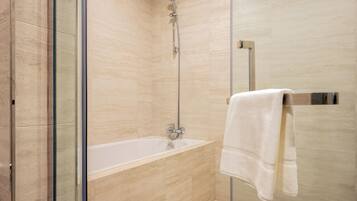 A modern bathroom with a glass-enclosed shower, a white bathtub, and a towel rack.