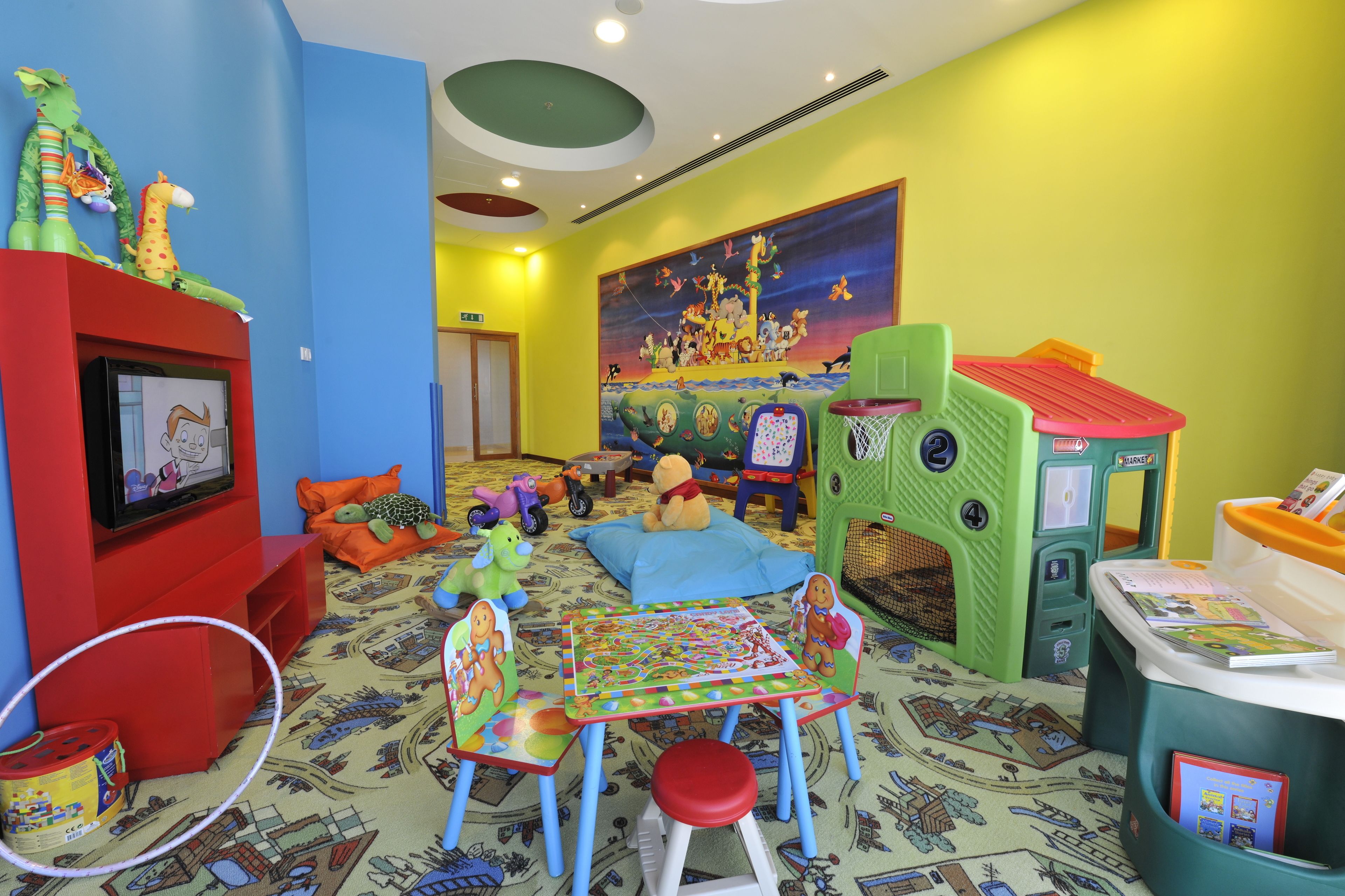 Uma sala de jogos infantil com televisão, espaço para brincar e decoração colorida.