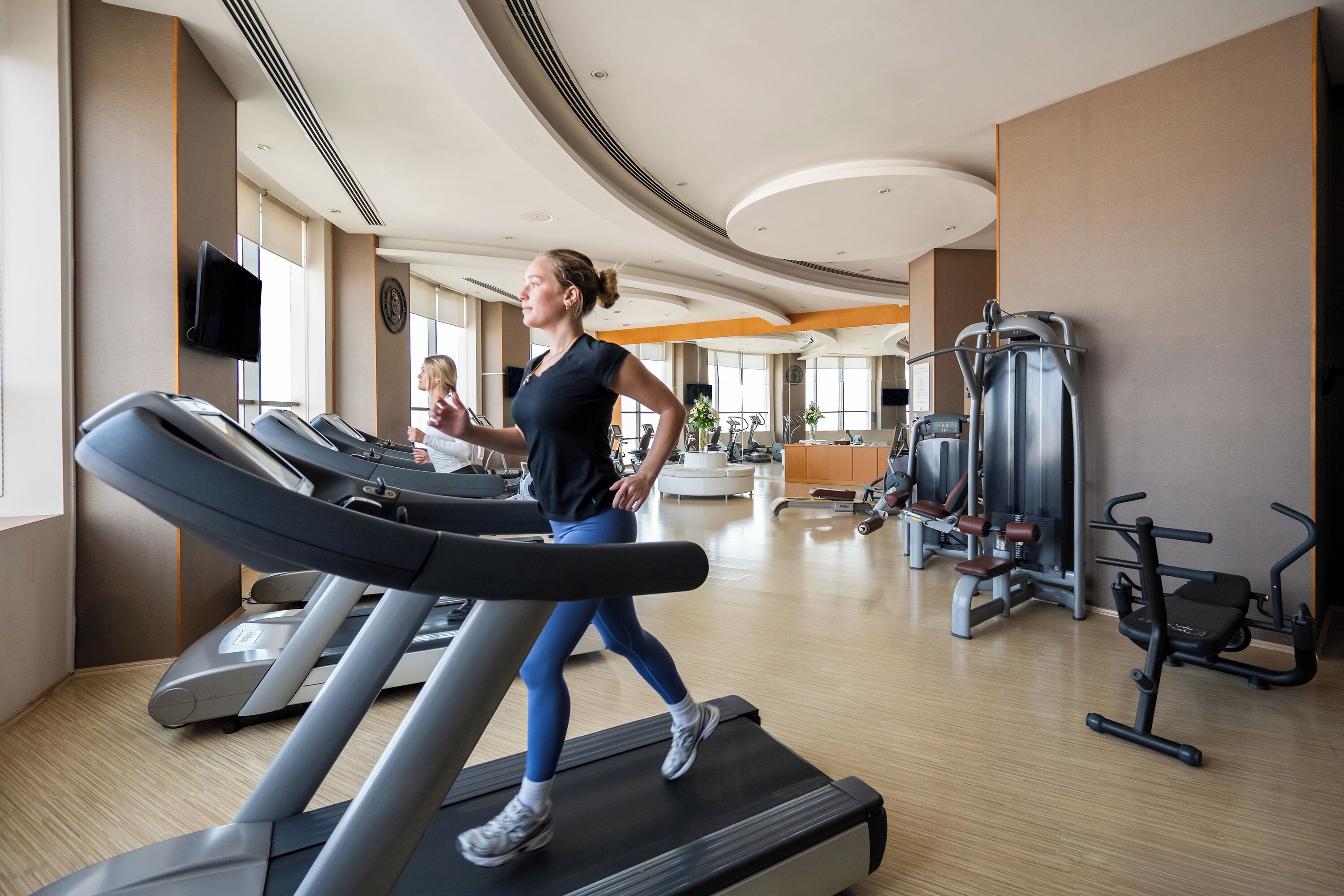 A gym with treadmills, exercise equipment, and large windows.