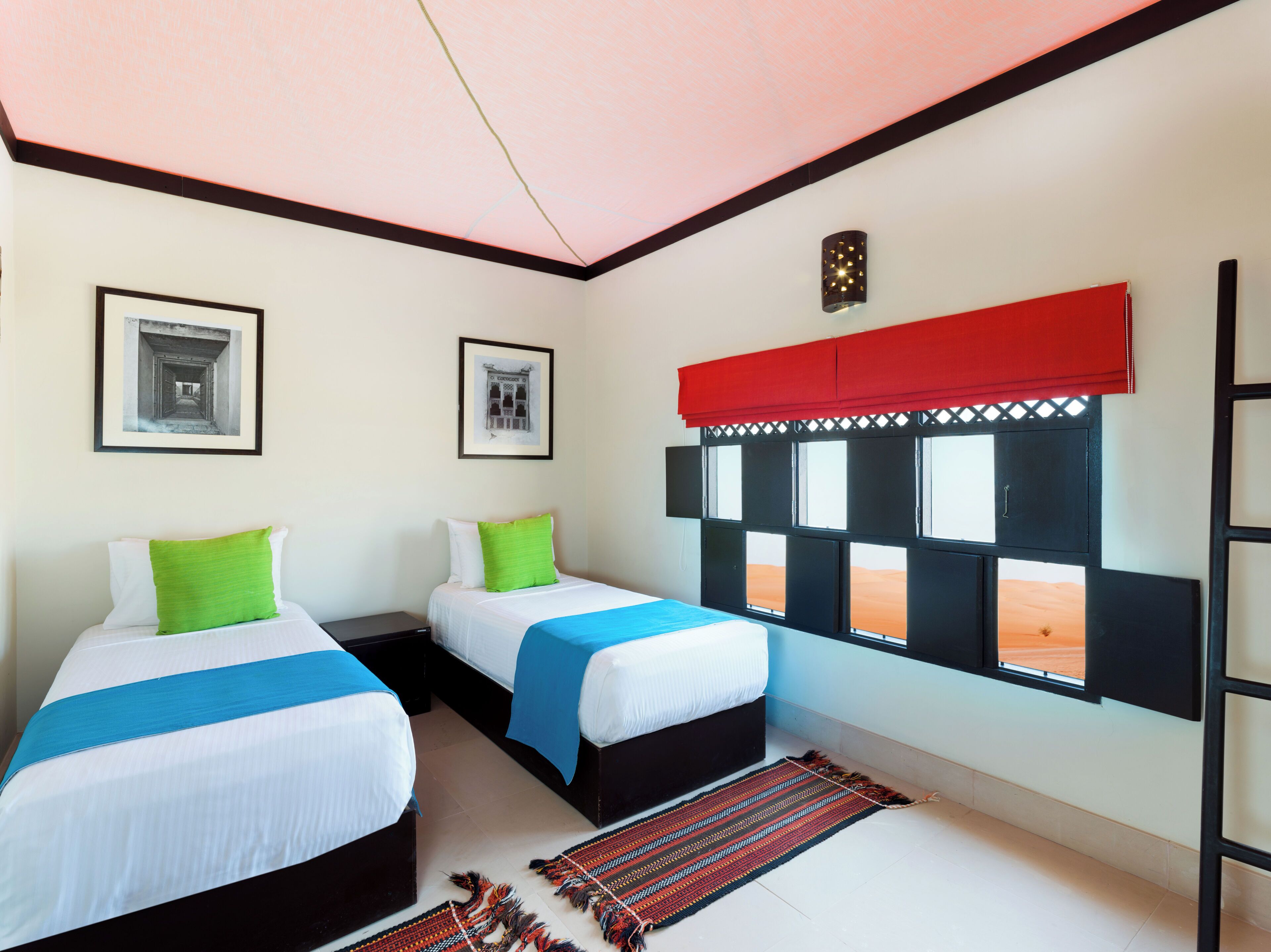 A room with two beds, a window with a view, and a red curtain.