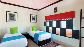 A room with two beds, a window with a view, and a red curtain.