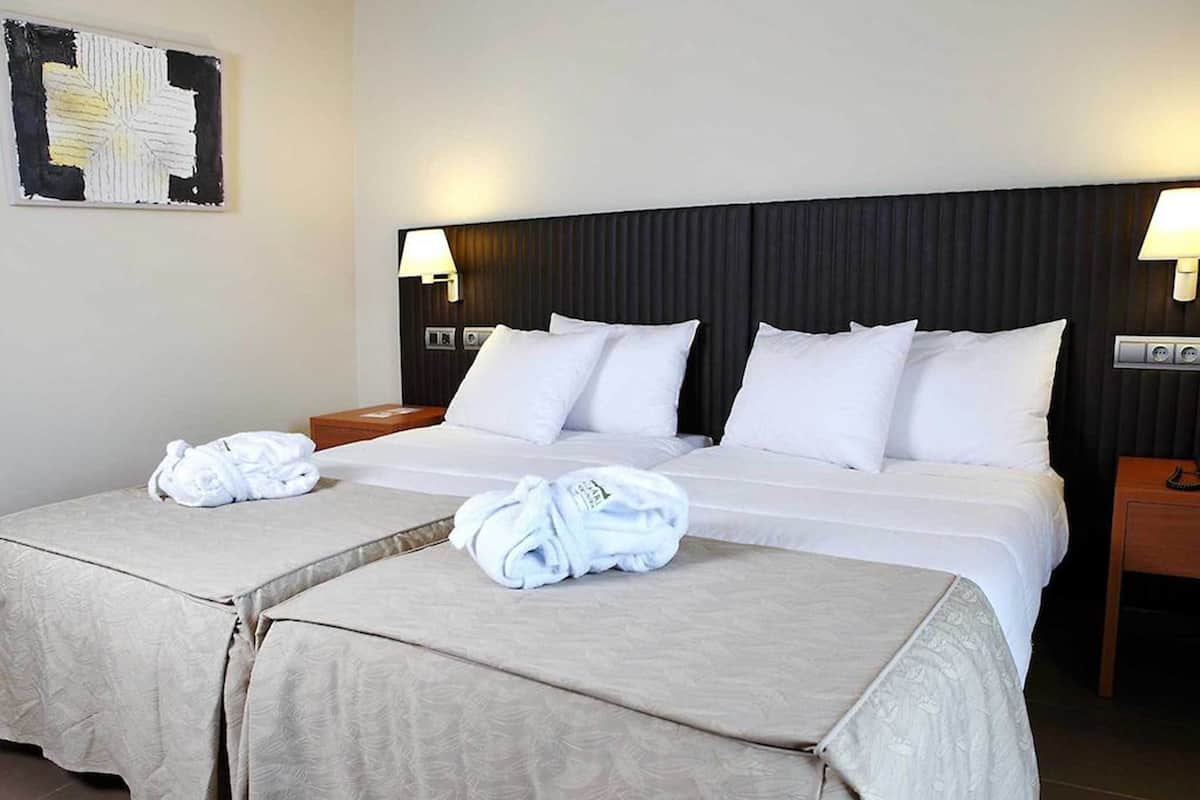 Een hotelkamer met twee bedden, witte lakens en handdoeken.