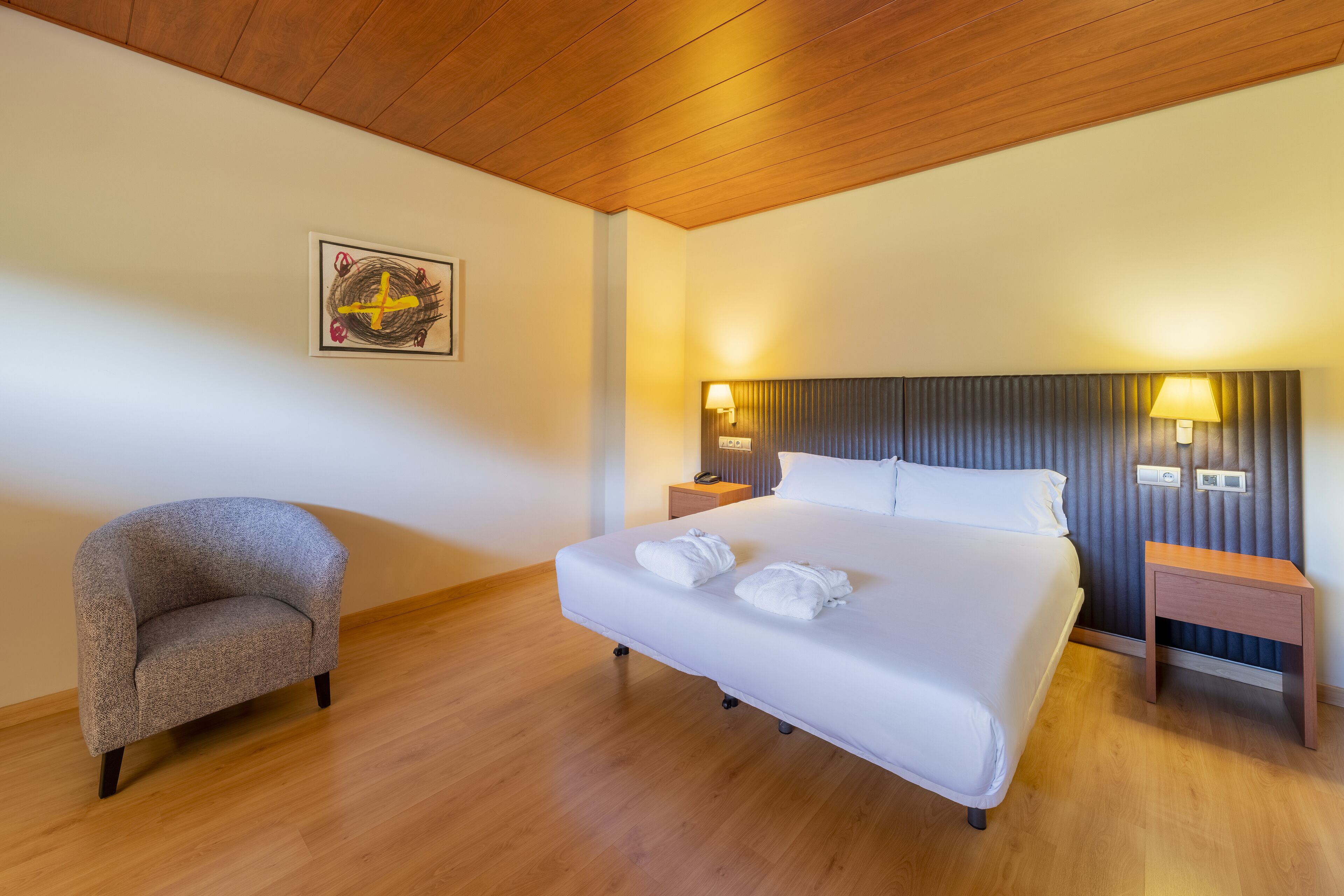 Een keurig ingerichte hotelkamer met een bed, een stoel en een kunstwerk aan de muur.