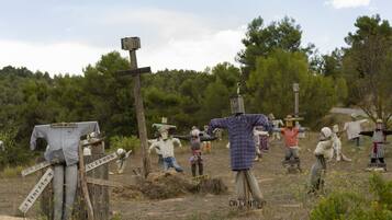 A rural outdoor scene with wooden structures and figures, including a sign that reads "ESTIMACELLES".