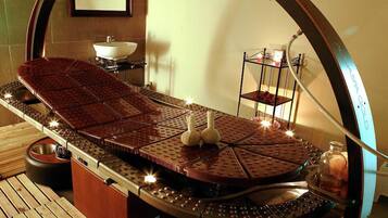 A sauna with a wooden bench, a small sink, and a shelf with decorative items.
