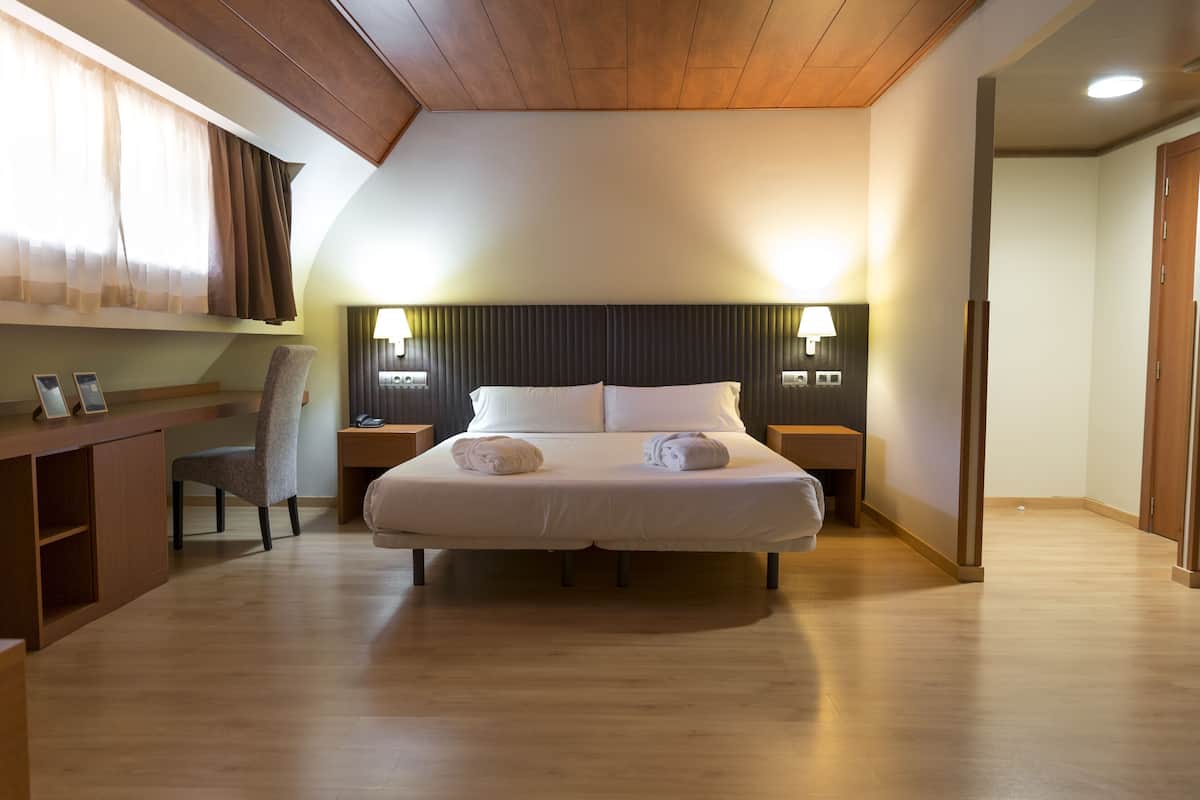 Een hotelkamer met een bed, bureau, stoel, nachtkastjes en lampen.