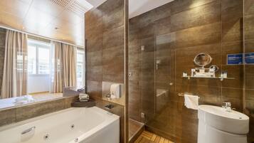A modern bathroom with a large bathtub, a glass shower enclosure, and a sink.