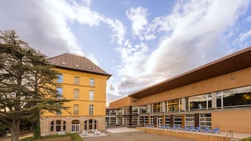 Ein Gebäude mit Innenhof, einem Baum und einer Reihe blauer Stühle.