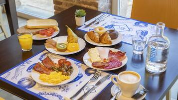 Una mesa de desayuno con platos de comida, un vaso de jugo de naranja, una botella de agua y una taza de café.